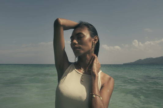 A woman standing in the ocean with her arms behind her head